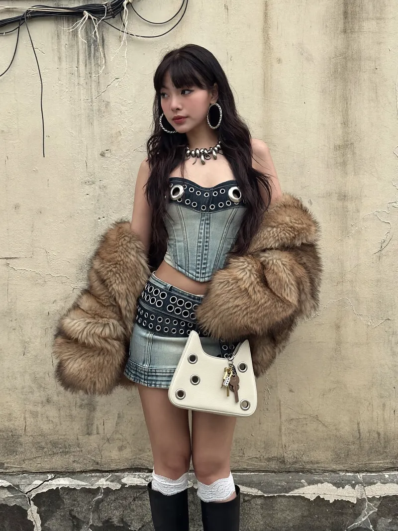 A medium shot captures a young Asian woman in a stylized out…